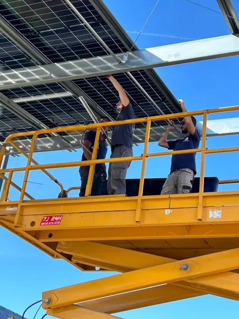 Techniciens posant les modules d’une ombrière depuis une nacelle